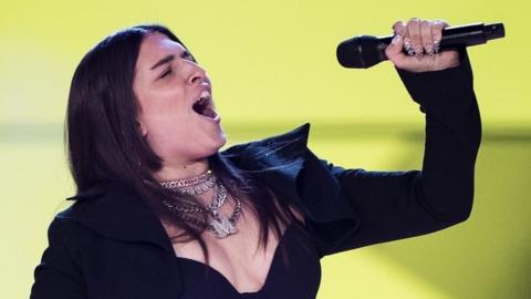 Mae Muller sings into a mic at Eurovision