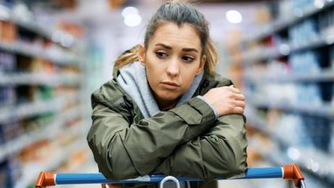 Woman leaning on a shopping trolley in a supermarket