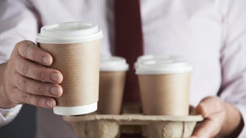 Man holding a tray of takeaway coffee