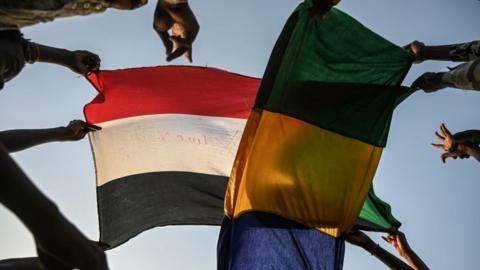 Sudanese protesters raise flags during a sit-in outside the army headquarters in the capital Khartoum on 29 April 2019