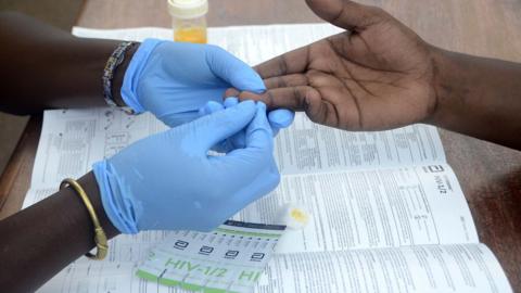 A close up of gloved hands taking blood samples for HIV testing in 2022