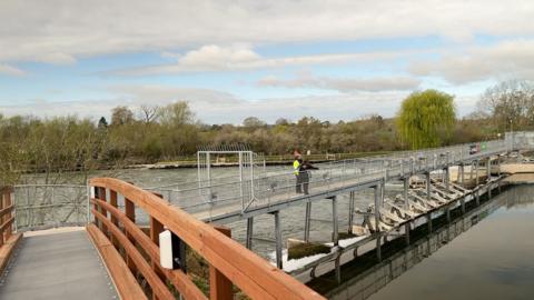 A new footbridge as seen from the wooden section of it looking at the weir.