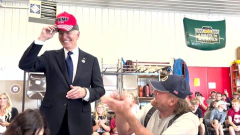 A smiling Joe Biden with 'Trump 2024' hat on his head