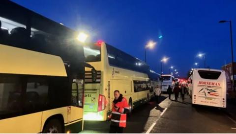 Fans queue by a waiting bus at St Mary's