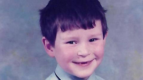 A school picture of Danny Leech - he has dark hair and is smiling mischievously at the camera