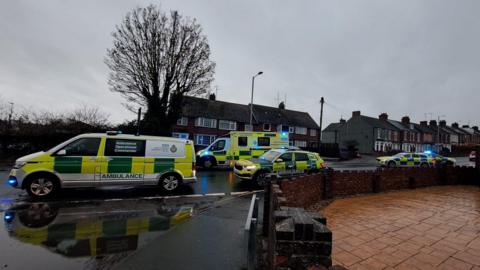 Emergency vehicles block a road in Harwich. There are two police cars and three ambulances