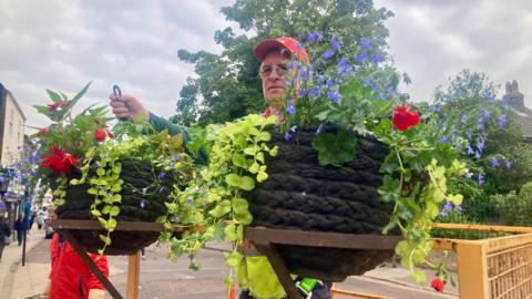 Man with two flowering hanging baskets