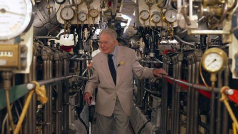 Roger wood holding the railing as he walks through the submarine