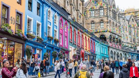tourists walking down a colourfully-painted street in Edinburgh