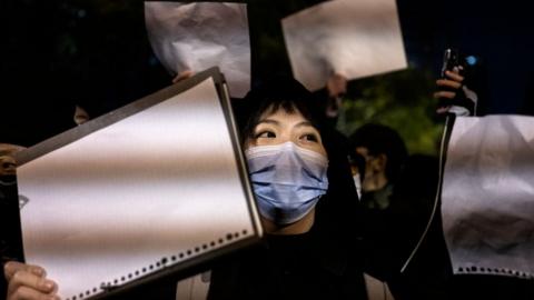 Activists hold up a white piece of paper against censorship during a zero-Covid protest