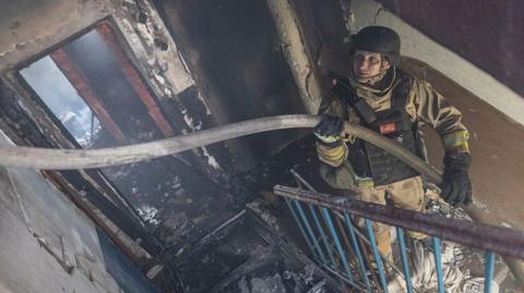 Ukrainian emergency service workers extinguish a fire in a residential building, after Russian shelling, in Kostiantynivka