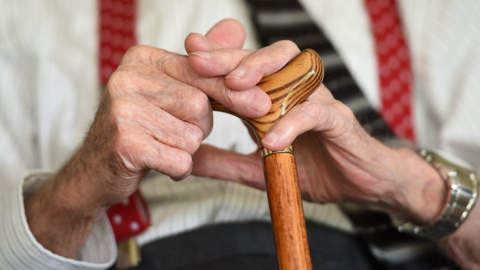 Hands of an older person with a walking stick