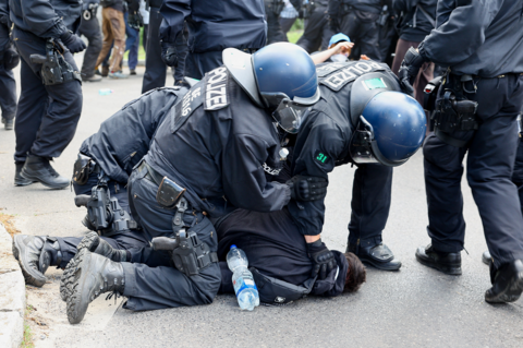 Police officers detain an activist during a protest against the expansion of Tesla Gigafactory in Gruenheide near Berlinm Germany