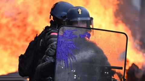 Police in Paris stand in front of a burning barricade