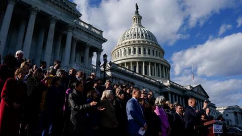 A large group of people stand on the steps of the US Capitol