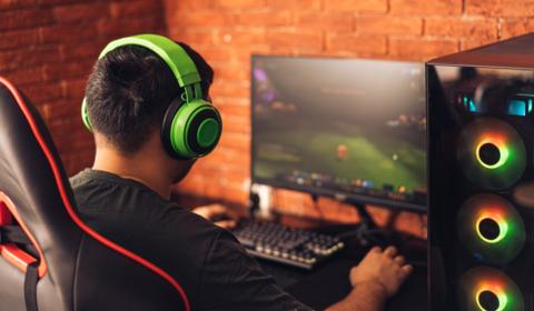 Young man sits with his back to the camera playing eSports on a PC 