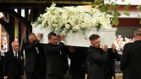 Men carrying a white coffin