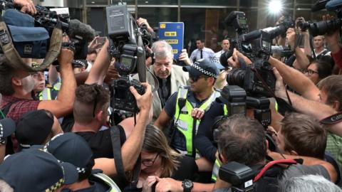 Cardinal George Pell is swarmed by media as he leaves a court in February