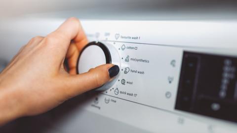 hand on washing machine controls