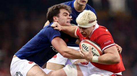 Aaron Wainwright of Wales is tackled by Damian Penaud of France
