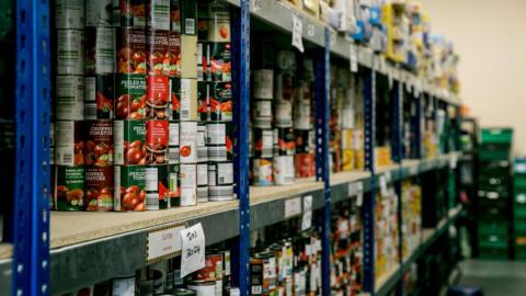 Shelves of canned food, including chopped tomatoes at a food hub. 