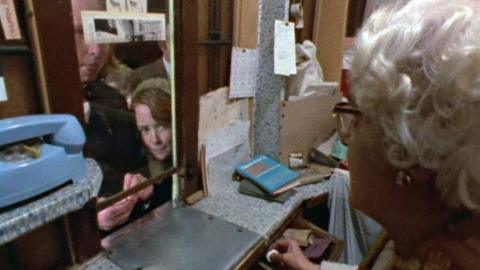 Children pay elderly woman, behind an old fashioned cinema booth. 