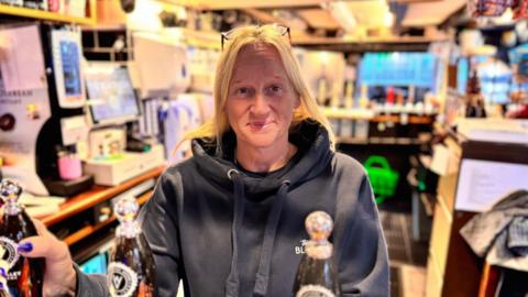 Maria Gooding standing at the bar of the Black Star pub in Stourport-on-Severn with her hand on a beer pump