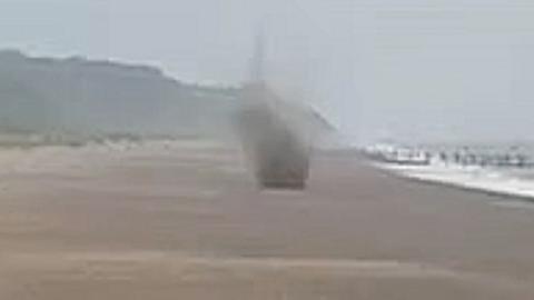 Mortar exploding on a beach.