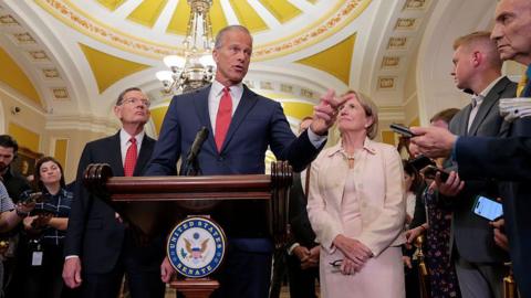 Senate Majority Leader John Thune speaks to reporters at the US Capitol. He is accompanied by other senators and speaking behind a podium with the Senate logo. 