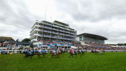 A general view as runners pass the winning post during The Aston Martin 'Dash' Handicap on Derby Day during the Derby Festival at Epsom Downs Racecourse on June 01, 2024 in Epsom, England.
