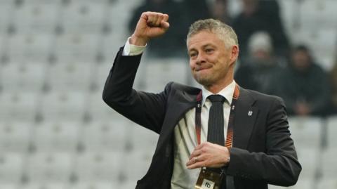 Ole Gunnar Solskjaer, wearing a suit, celebrates