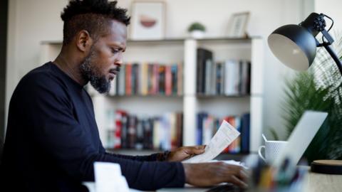 Man paying his utility bills online and looking worried - stock photo