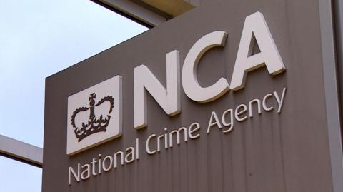 The National Crime Agency logo on a corporate totem. There are white letters on a grey background.