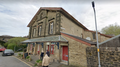 Settle Victoria Hall, a sand-coloured brick building with red doors and windows 