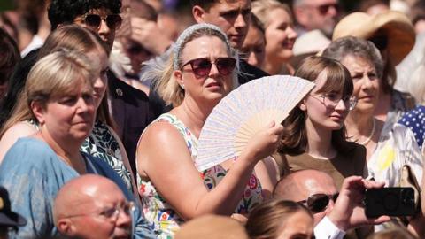 A woman fans herself at the Duke of Edinburgh Gold Award celebrations at Buckingham Palace, London