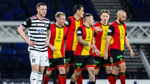 Queen's Park's Leon King (L) looks dejected as the Partick players celebrate Logan Chalmers' opening goal during a William Hill Championship match between Queen's Park and Partick Thistle at Hampden Park,