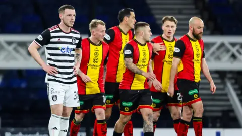 Queen's Park's Leon King (L) looks dejected as the Partick players celebrate Logan Chalmers' opening goal during a William Hill Championship match between Queen's Park and Partick Thistle at Hampden Park,