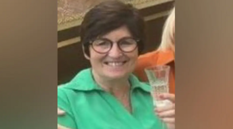 Donna Brighton in green top holding a glass