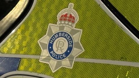 A close-up of a Humberside Police logo on a police car.