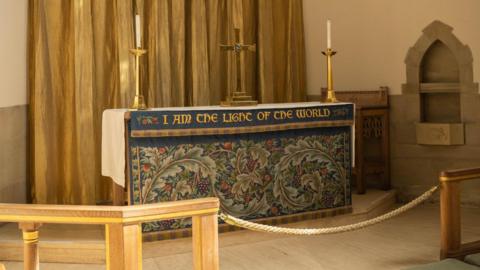 An altar cloth with leaves and fruits sat atop an altar at Bradford Cathedral with two gold candles on top