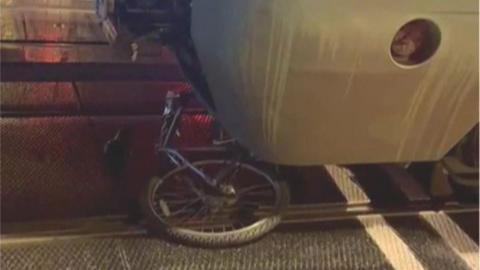 A bicycle is crushed under a train at night. 