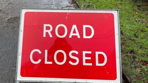 Close up of a rectangular street sign that says "Road closed" in capital letters of white on red