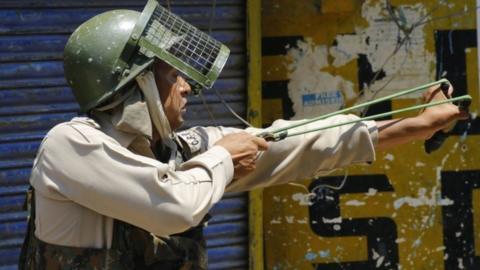 An Indian paramilitary soldier fires a catapult at Kashmiri Muslim protesters during clashes in Srinagar (08 July 29017)