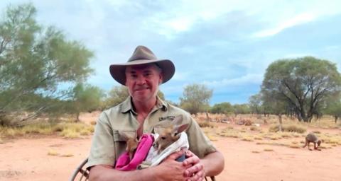 Chris "Brolga" Barns holding a baby Kangaroo.