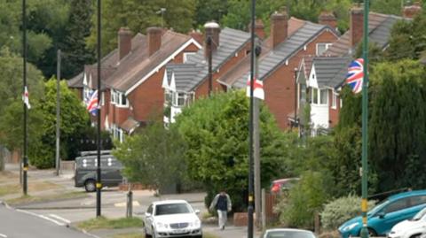 Rows of houses with England flags flying on lampposts outside