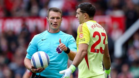 Referee Thomas Bramall (left) speaks to Aston Villa goalkeeper Emi Martinez (right)