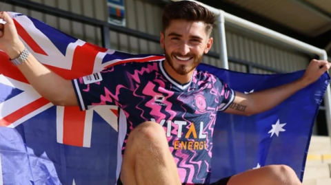 Josh Cavallo with the Australian flag after signing for Peterborough Sports