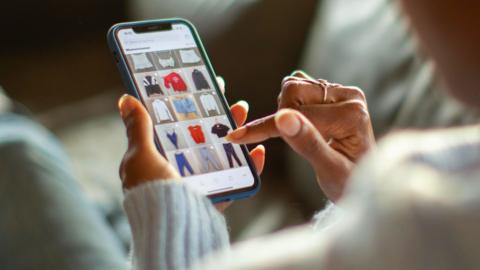 A woman shops for clothes on her phone