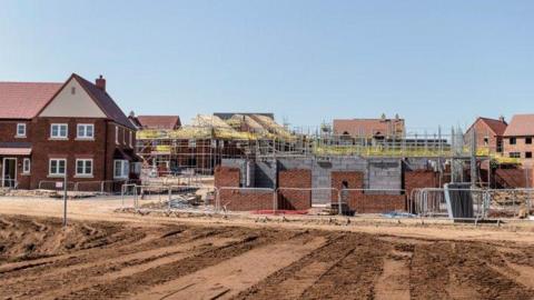 A generic image of a residential building site with red brick homes in a variety of states of development.