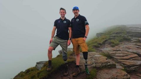 Rich Potter and Rich Davies standing on hill wearing polo shirts and shorts